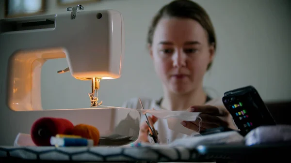 Mujer joven diseñadora cosiendo una máscara usando una máquina de coser —  Fotos de Stock