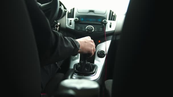 Homem jovem dirigindo um carro usando o navegador - muda a velocidade na caixa de transmissão — Vídeo de Stock