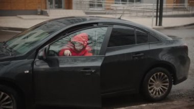 Bir kurye arabadan çıkar ve pizzayı teslim eder.