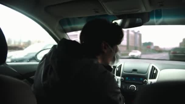 Fiatal férfi tapasztalatlan vezető védő maszk vezetés egy autó rossz időben, és idegesen körülnézett — Stock videók