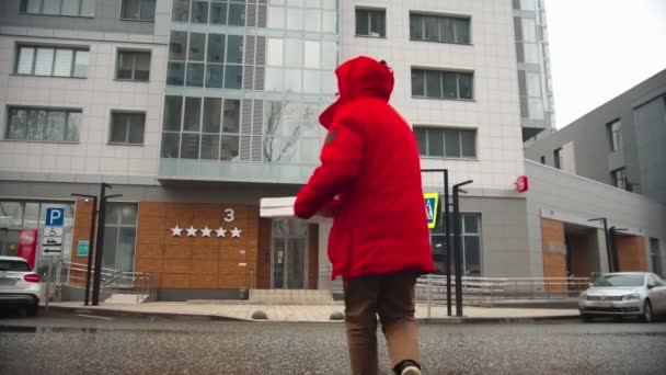 Ein Zusteller schaut sich um und überquert die Straße zu einem Hotel — Stockvideo