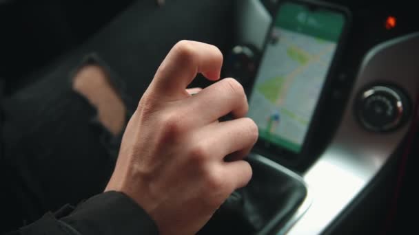 Молодой человек за рулем автомобиля с помощью навигатора - переключает скорость при передаче — стоковое видео