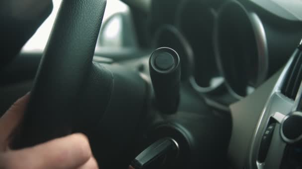 A fiatalember autót vezet, és bekapcsolja az ablaktörlőt. — Stock videók
