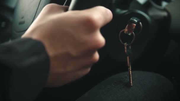 Joven conduciendo un coche - sosteniendo el volante y la llave en el encendido — Vídeo de stock