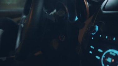 Genç bir adam arabada oturur ve kontağı çevirir.