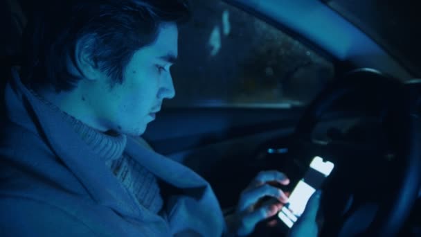 Joven guapo sentado en el coche y usando el teléfono — Vídeos de Stock