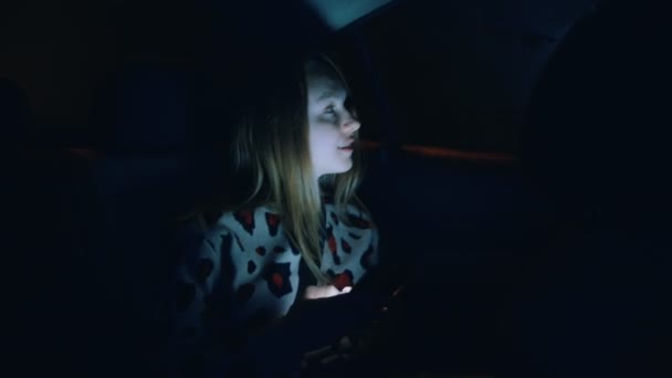 Молодая женщина на заднем сиденье машины ночью — стоковое видео