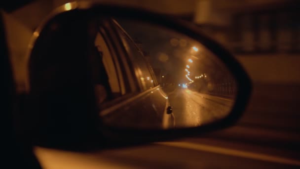 Espejo lateral de un automóvil mientras se mueve - montando en la noche lluviosa — Vídeo de stock