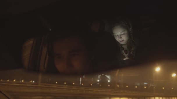 자동차 뒷자리에 앉은 젊은 여자가 거울에서 자기를 쳐다보고 있는 전화 기사를 보고 있는 모습 — 비디오