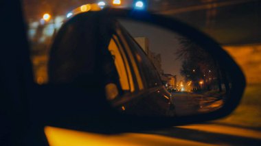 Gece giden bir otomobilin yan aynası.