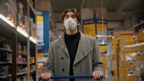 Young man in protective mask and grey coat pushing the pushcart — Stock Video