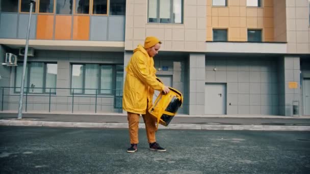 Man kurir i gula kläder levererar mat - öppnar sin ryggsäck och drar ut pizzalådorna — Stockvideo