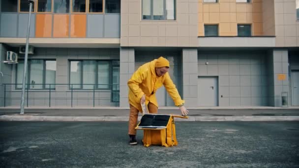 Uomo corriere in abiti gialli consegna cibo gocce scatole di pizza sul pavimento — Video Stock
