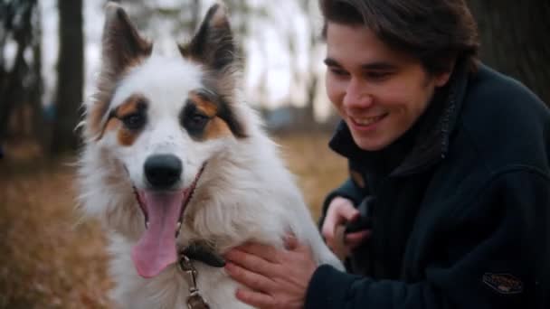 Young man with his brother walking with dog outdoors at autumn park — Stock Video