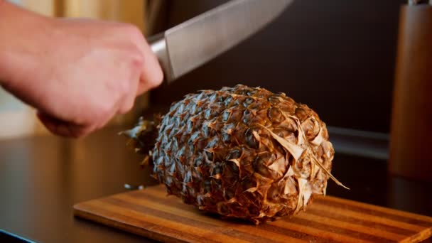 Разрезание спелого ананаса пополам ножом — стоковое видео