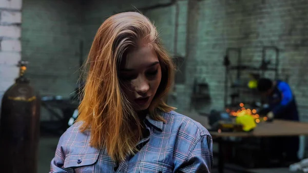 Молодая красивая женщина с рыжими волосами, стоящая в мастерской — стоковое фото