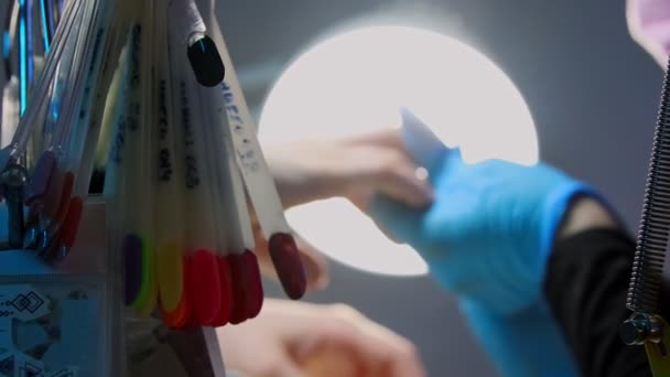 Manicure master w masce robi manicure - lakier do paznokci kolory na próbkach na pierwszym planie — Wideo stockowe
