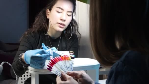Manicure meester met haar cliënt jonge vrouw kiezen van de kleur van nagellak op de monsters — Stockvideo