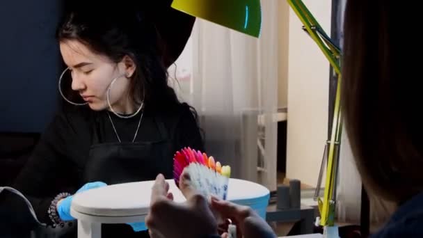 サンプル上のネイルポリッシュの色を選択する彼女のクライアントの女性とマニキュアマスター — ストック動画
