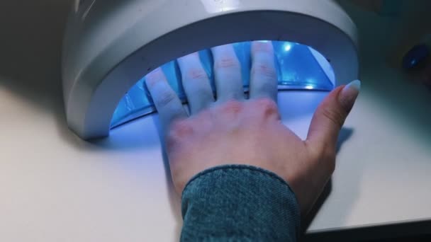 Doing manicure - hand van jonge vrouw in UV-lamp gel polish manicure — Stockvideo