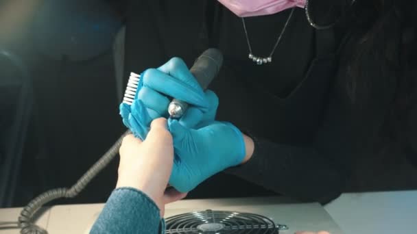 Manicure master w masce robi manicure - przygotowuje paznokieć do pokrycia i czyści naskórek za pomocą urządzenia — Wideo stockowe