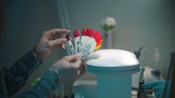 Mujer joven eligiendo el color del esmalte de uñas en las muestras — Vídeo de stock