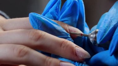 Manikür ustası manikür yapıyor - alet kullanarak tırnak derisini temizliyor