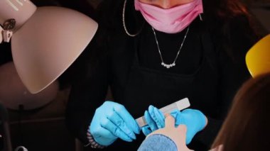 Usta manikür yapıyor. Güzellik salonunda tırnak törpüleyerek tırnaklarını törpülüyor.