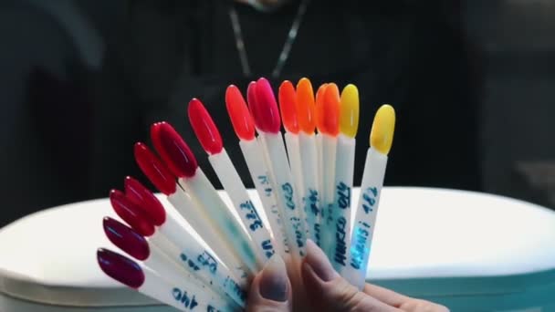 Escolhendo a cor quente do esmalte nas amostras — Vídeo de Stock