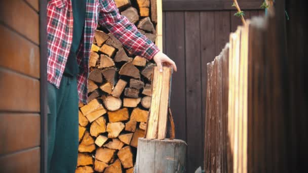 Mladý muž seká dřevo na půl sekerou. — Stock video