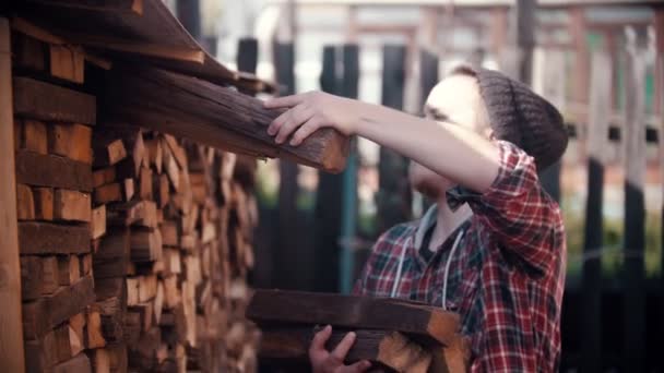 Genç oduncu kır evindeki standa kütük koyuyor. — Stok video