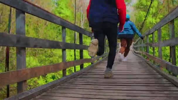 Joven hombre y mujer corriendo en el puente - hombre se detiene para atar sus zapatos — Vídeo de stock