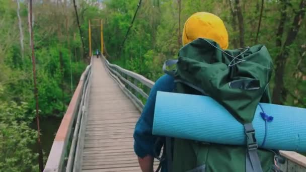 Fiatal férfi utazó egy nagy hátizsák sétál a hídon — Stock videók