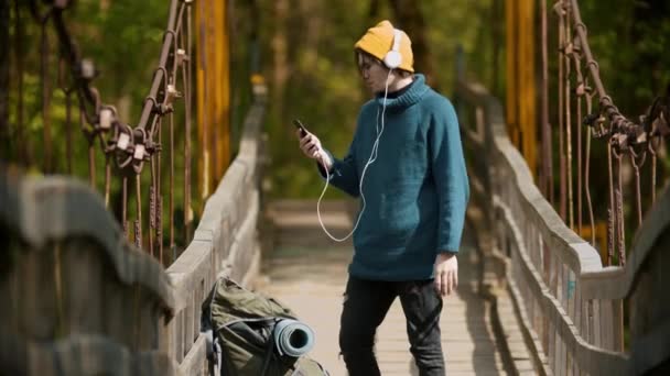 Joven viajero de pie en el puente y tener un chat de vídeo con su amigo — Vídeos de Stock