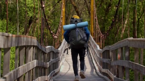 Ung man med stor ryggsäck på bron i skogen — Stockvideo