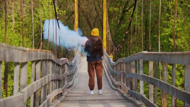 Jonge vrouw op de brug steekt vuur op en rent naar voren — Stockvideo