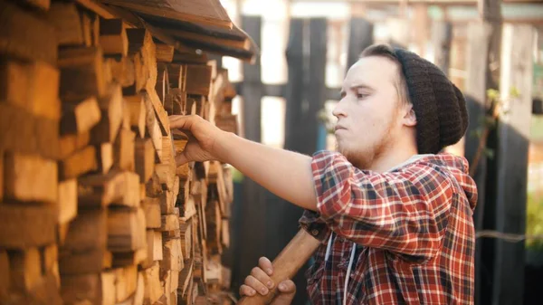 Jongeman houthakker met bijl zet het hout van de standaard — Stockfoto