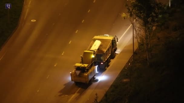 Een asfalt wasmachine rijdt 's nachts op de weg — Stockvideo