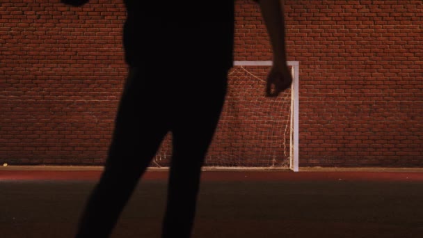 Junger Mann spielt nachts auf Spielplatz Fußball — Stockvideo
