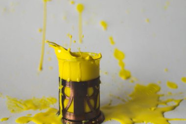 Parlak bir sıvıyla uçan bir bardak beyaz arkaplanda sıçrıyor.