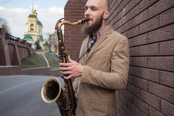 Şehrin sokaklarında gözlüklü yakışıklı bir erkek saksafoncu oynuyor.