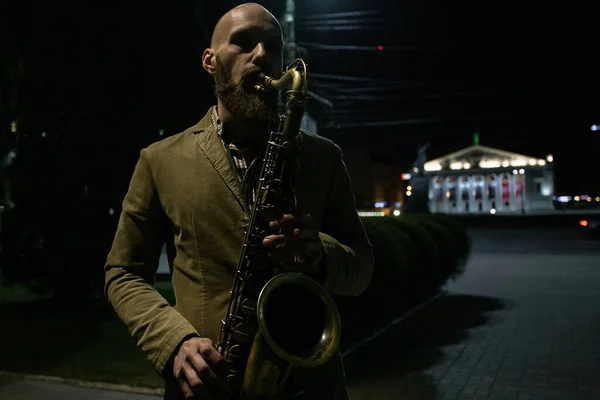 a handsome male saxophonist with glasses plays on the streets of the city
