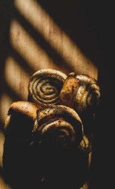 Tahta bir tahtanın üzerinde, güzel, sıcak bir ışıkla aydınlatılmış haşlanmış ve haşhaş tohumlu çörekler var. Ona yakın bir bıçak.