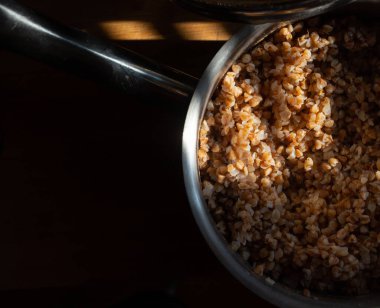 Yeni hazırlanmış karabuğday lapası küçük çelik bir tavada, sapı güzel, sıcak bir ışıkta.