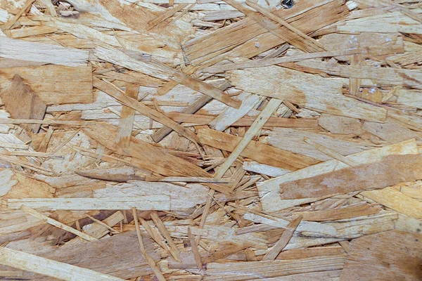 Çizgili tahta işletim sistemi kahverengi çiplerden yapılmış, tahta bir arka planda zımparalanmış. Ahşap kaplama yonga tahtası, yoğun, pürüzsüz yüzeyler..