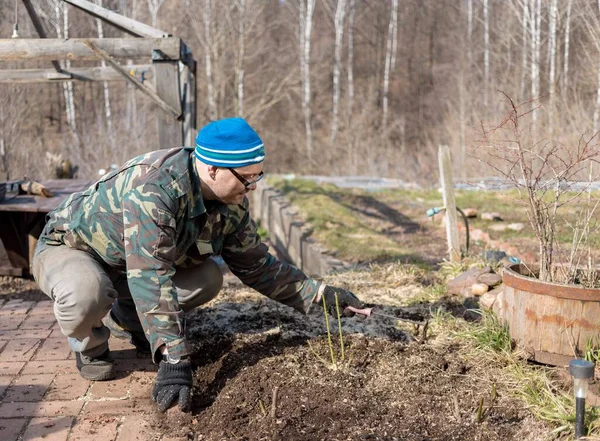 Bahçede tek tekerlekli arabası olan iş elbiseli bir adam. Kameranın sarı tekerleğine doğru kaydırarak aşağı yuvarlıyor.