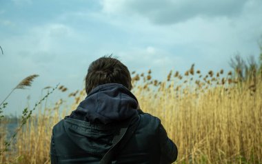 Adam arkadan çekiliyor, yüzünü göremiyoruz rüzgarda sallanan uzun kuru gövdelerin arka planında.. 