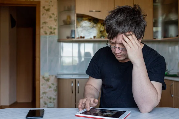 Bir adam evde bir masada oturuyor. Ofis evde. Adam kafasını tuttu, tabletteki bilgileri inceledi, anlamaya çabaladı, çalıştı. Model değil, sıradan bir insan. Adam dikkatle tablet ekranına bakıyor.