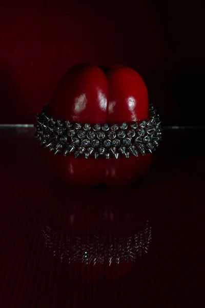 一个由不同种类的闪亮钢珠制成的手镯被放在新鲜的红辣椒上 玻璃上的倒影真漂亮 深红色背景 — 图库照片
