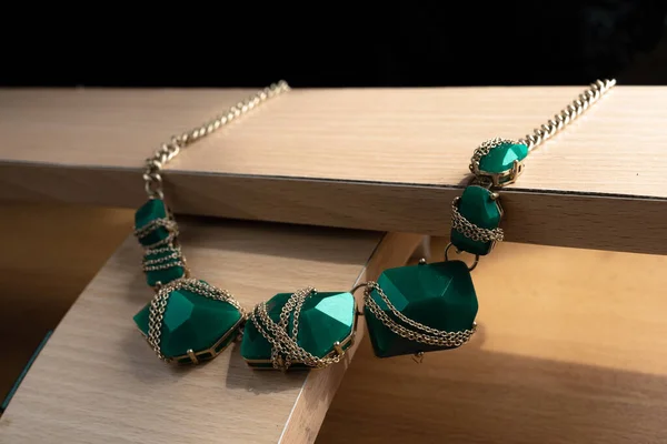 Bijouterie. Kolye, hafif ahşabın geometrik bileşiminin üzerinde duruyor. Karanlık arkaplanın arkasında.